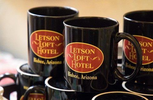 Nine mugs black mugs with red and yellow oval logos stacked on each other