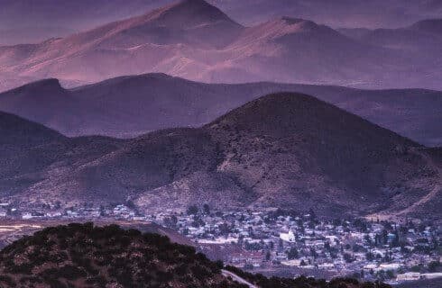 Early morning view of a small town down in a valley with mountain ranges in the background