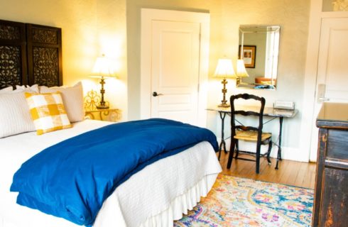 Elegant guest room with bed, decorative brown headboard, writing desk and TV console