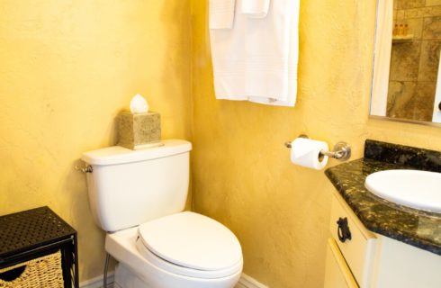 Bathroom with yellow walls, toilet, and black and white vanity with sink