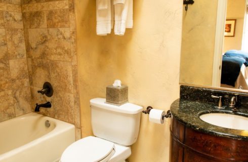 Bathroom with tiled shower, toilet, dark brown vanity and large mirror
