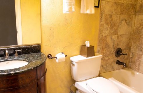 Bathroom with cream walls, tiled shower with tub, toilet and dark brown vanity