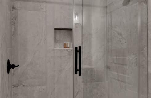glass enclosed tiled shower on walls and floor with bronze fixtures