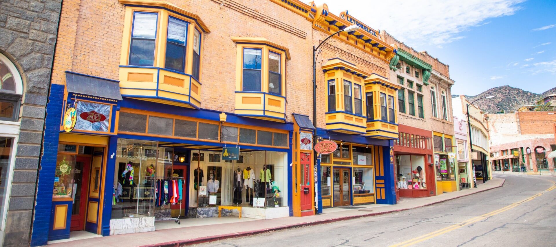 Quiet empty street showing several storefronts with colorful, decorative windows