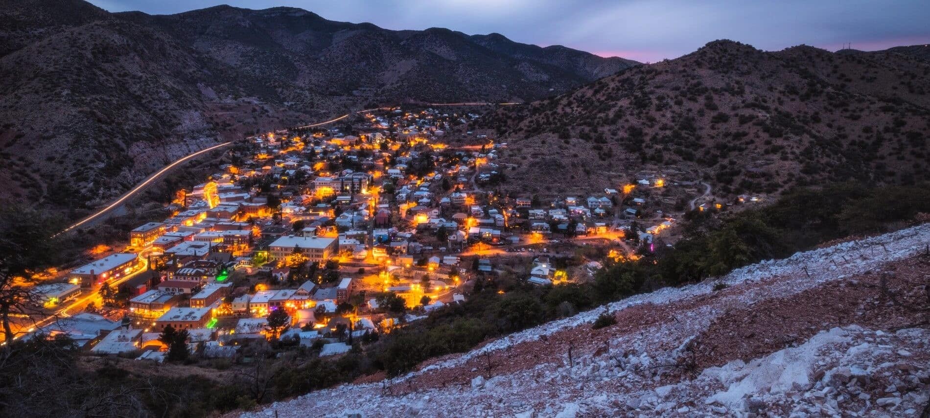 Overhead view of small town lit up at night in a valley with mountains on all sides