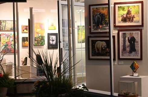 A glass storefront featuring several colorful pieces of art on the walls