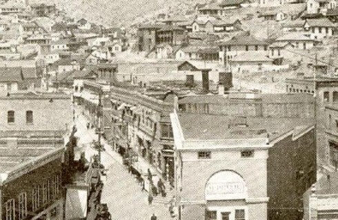 A historic black and white view of the downtown of a city showing lots of buildings and a main street